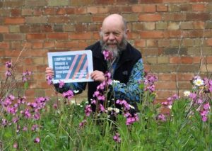 Man in flowers holding CEE Bill leaflet