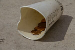 coins in an empty paper coffee cup